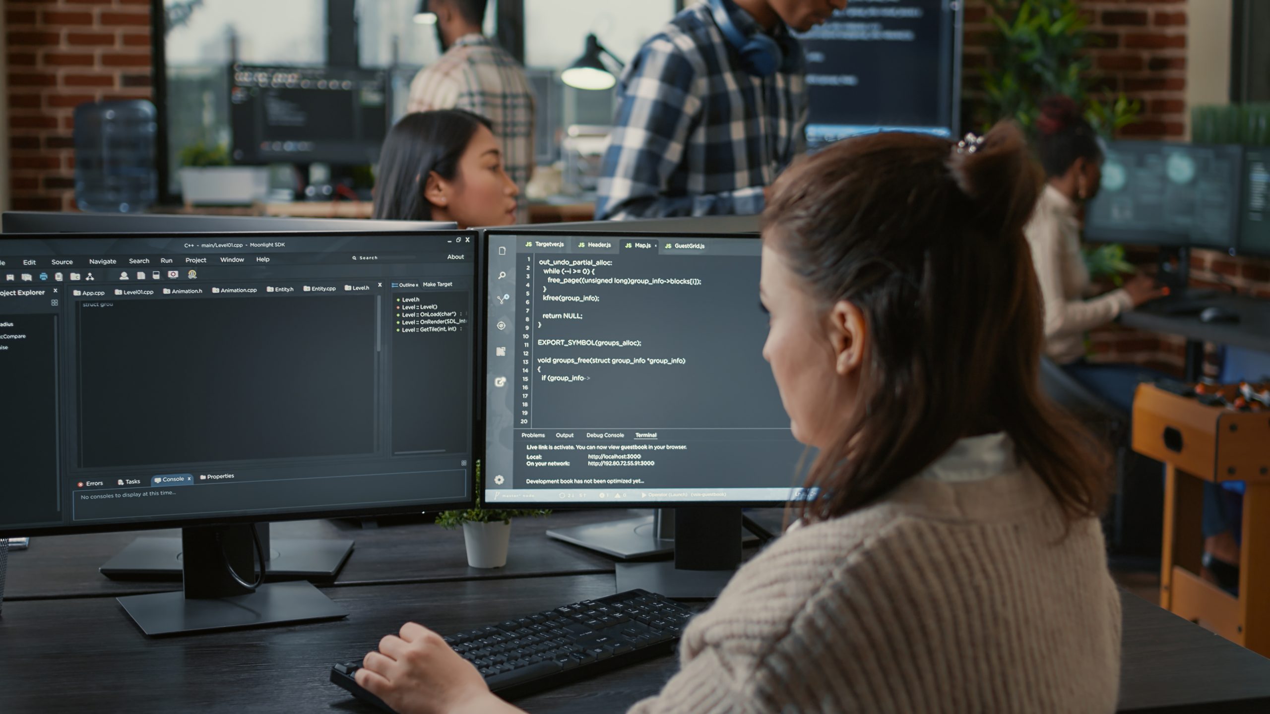 Software programer writing code in front of multiple computer screens